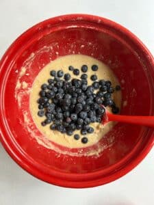 Frozen blueberries added to batter in the red bowl.