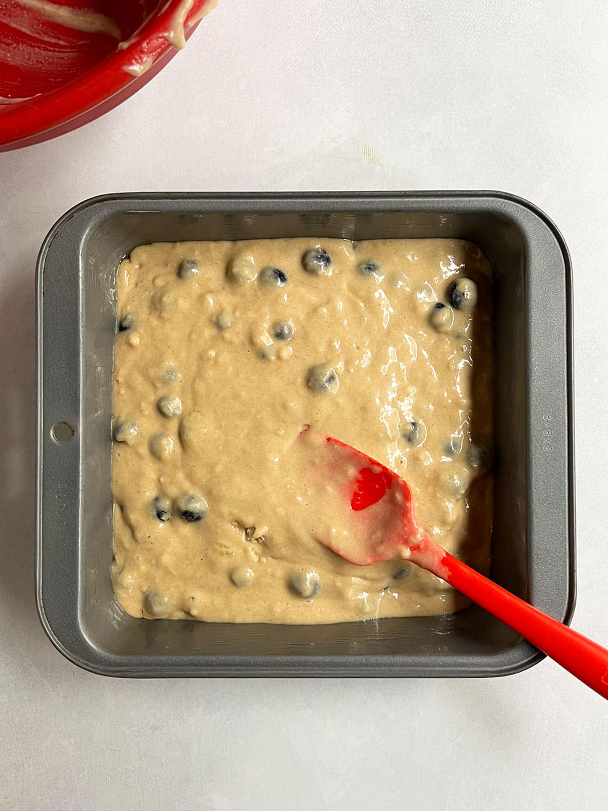 Blueberry loaf cake batter in the square cake pan ready to bake.