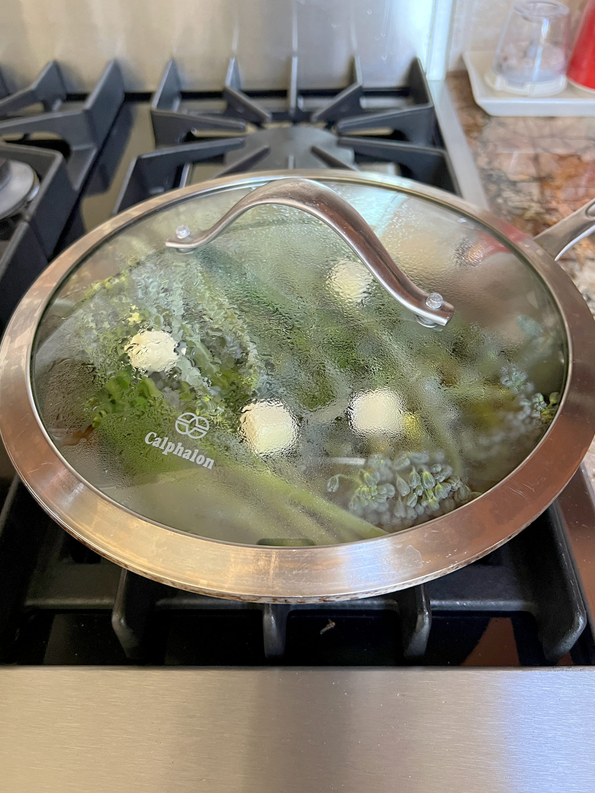 Broccolini pan covered but liquid accumulating on the clear glass cover.
