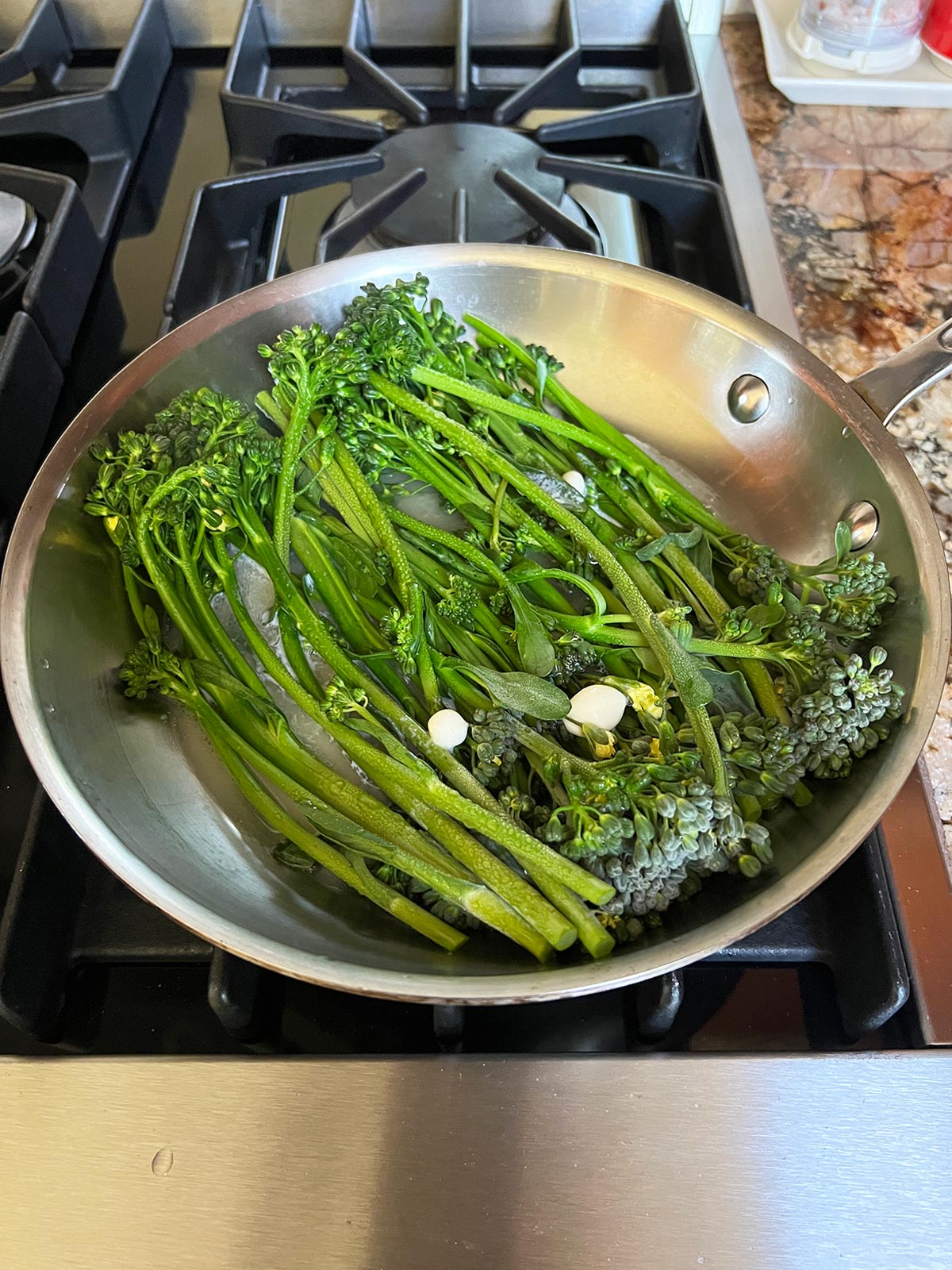Baby broccoli cooked in pan with the cover off.