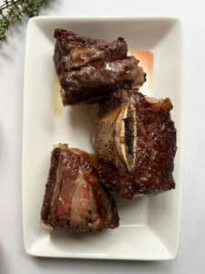 Seared flanken ribs on a white plate resting.