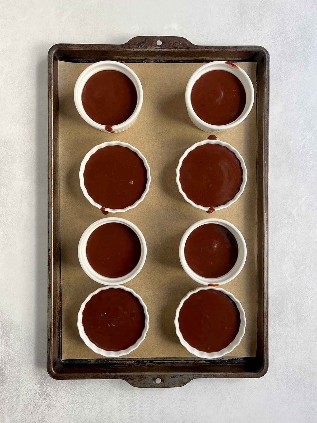 Eight serving bowls filled on a parchment-lined baking tray ready to go in the refrigerator.
