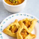 Pinterest image showing hamantaschen filled with apricot butter and a bowl of apricot lekvar in the background.
