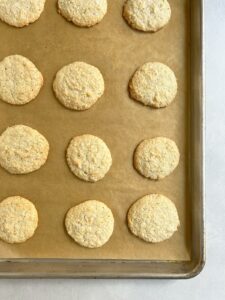 Flatter version of baked Passover macaroons on a parchment lined baking sheet.