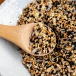 Everything bagel seasoning in a white bowl with a wooden spooful on top.