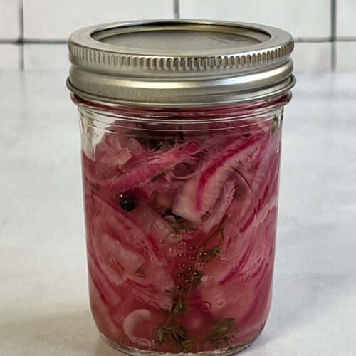 Pickled red onions in a canning jar close up view of some that are ready to eat.