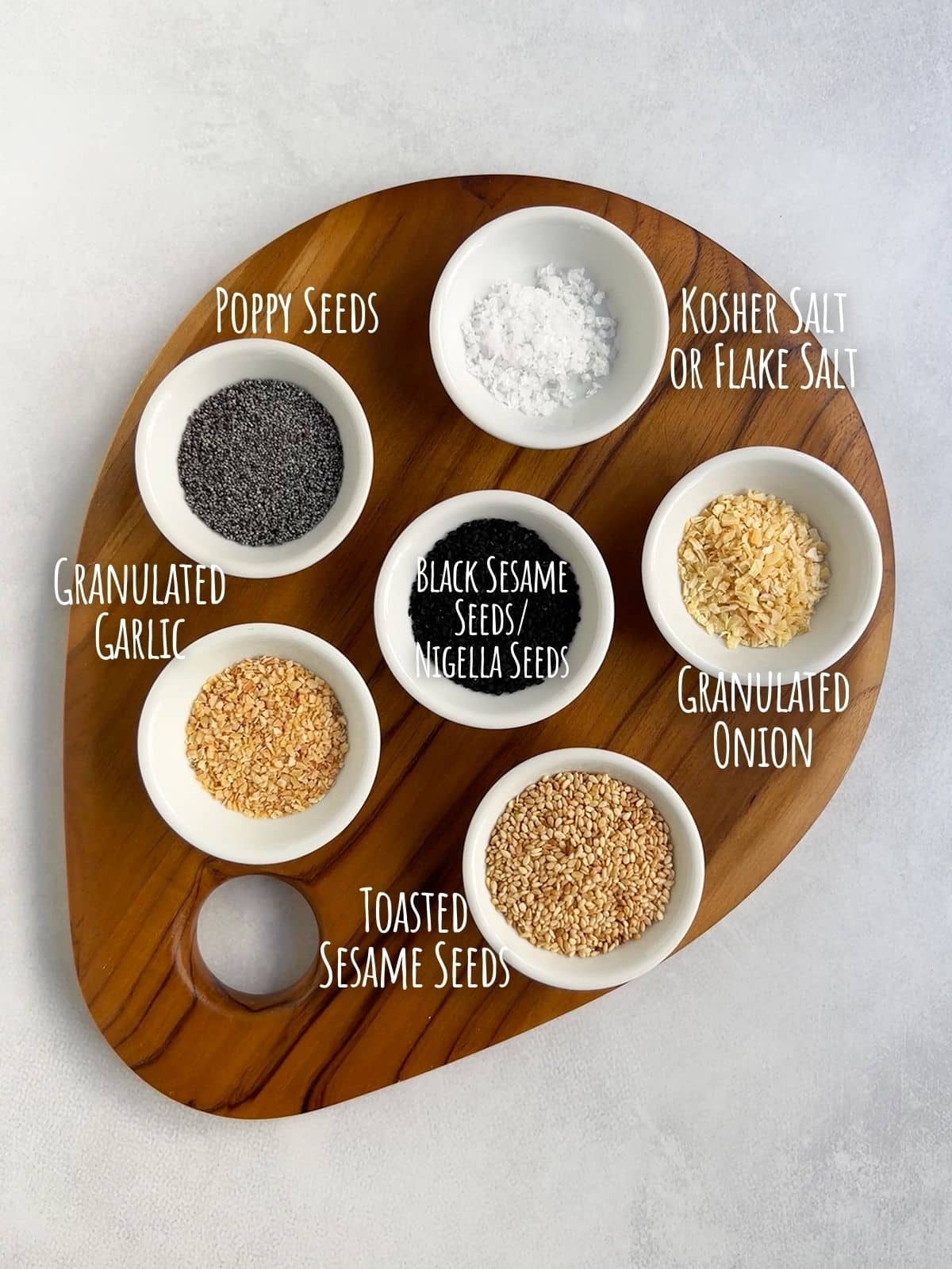 Ingredient shot for everything bagel seasoning recipe showing salt, poppy seeds, sesame seeds, nigella seeds and granulated onion and garlic.