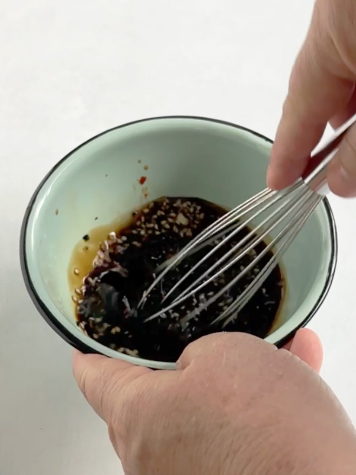 Beth whisking shoyu sauce in a light blue bowl.